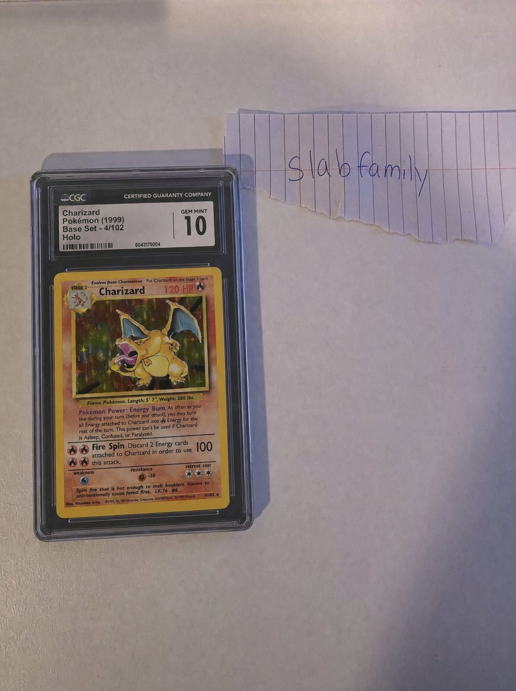 Intake photo: the CGC slab of Charizard — Holo beside a handwritten "slab family" note